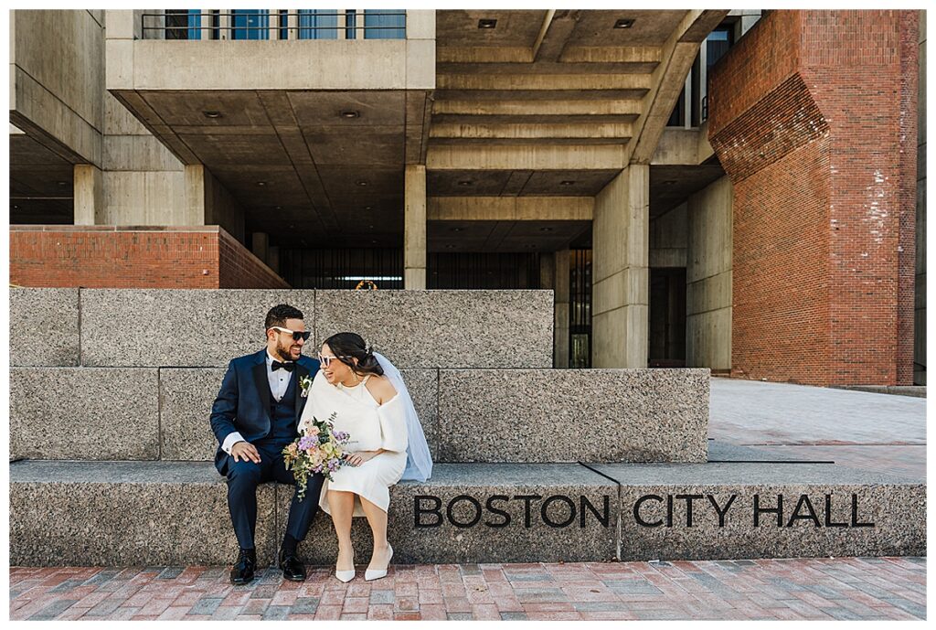 A couple sits outside Boston City Hall on the day of their elopement.