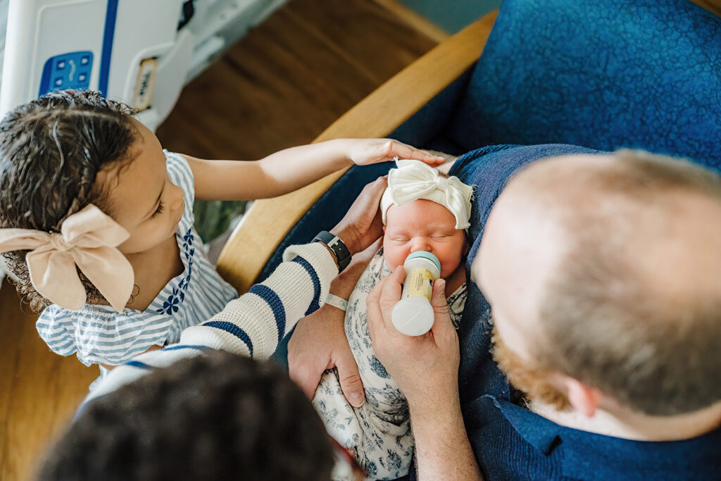 Lifestyle newborn session in Boston home, toddler meeting newborn sibling for the first time.