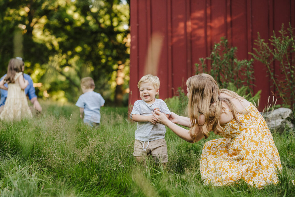Summer family photos near Boston with coordinated warm-toned outfits in a green landscape